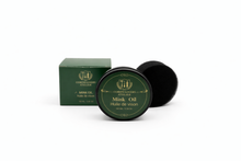 Green container of mink oil with a black lid on a white background